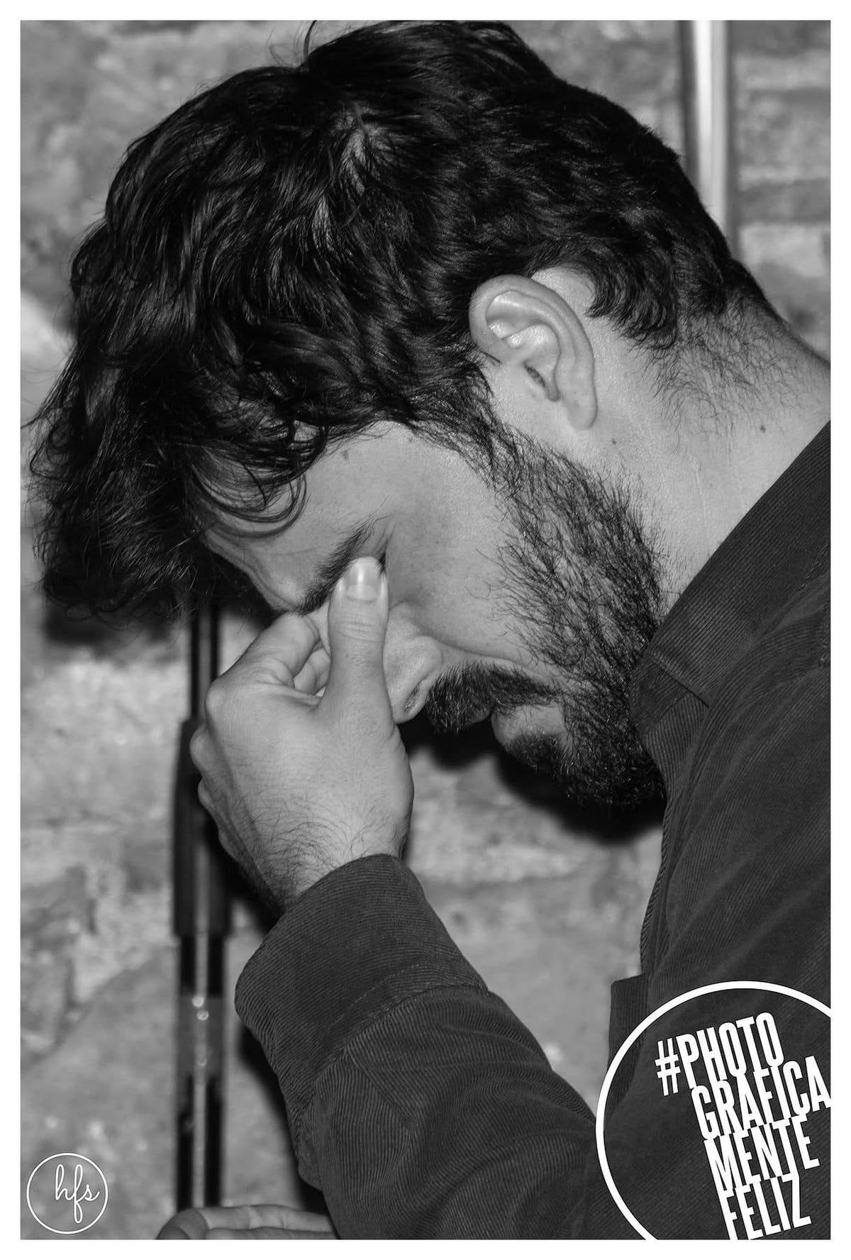 Primer plano en blanco y negro del mismo músico de pelo oscuro y ondulado, cabeza inclinada hacia abajo con los ojos cerrados y una mano cerca de la boca, en actitud concentrada; se…