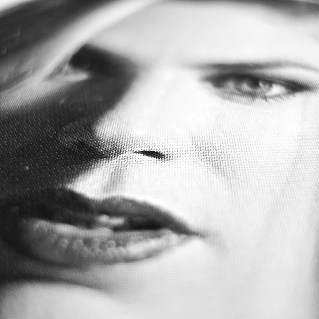 Segundo macro en blanco y negro de un rostro impreso sobre tela, esta vez de rasgos mas femeninos, con el ojo derecho nitido y el resto del rostro en sombra o desenfocado.