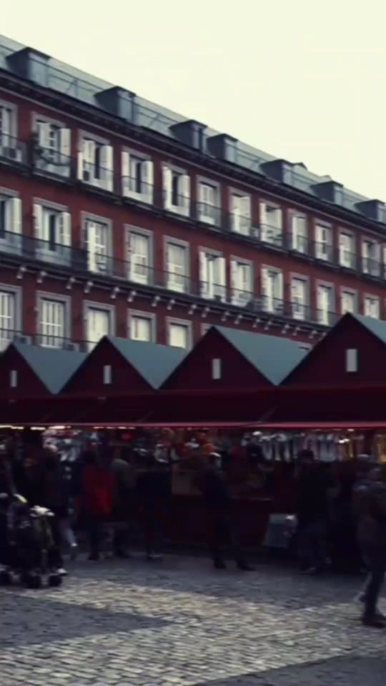 Secuencia que mezcla una fachada con balcón y el cartel "La Fabrique de Belgique" con gente cruzando en la calle, una terraza de bar concurrida bajo un toldo, un adorno circular tipo reloj…