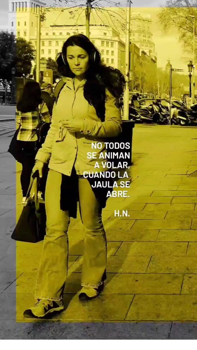 Fotografía fija con viraje amarillo y gris de una mujer caminando por una avenida urbana con auriculares y una chaqueta clara, cargando un bolso; al fondo se ven edificios históricos, motos…