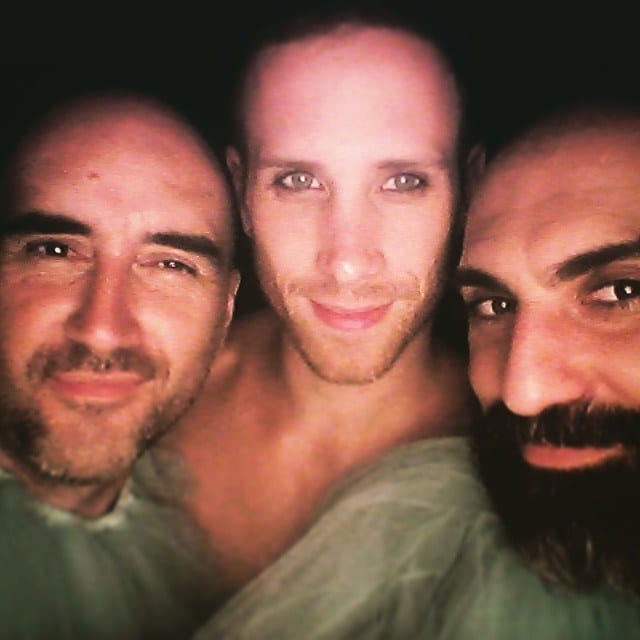 Selfie grupal de tres hombres muy pegados al lente: uno con barba y entradas, otro pelado y pelirrojo sin remera, y un tercero con barba tupida oscura.