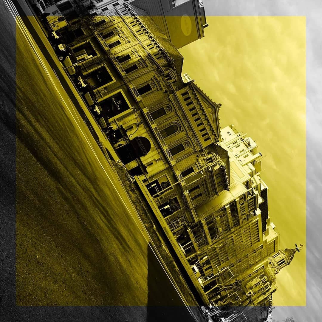Vista de una fachada ornamentada de un edificio clasico, encuadrada en diagonal con la camara girada, tambien en blanco y negro con viraje amarillo.