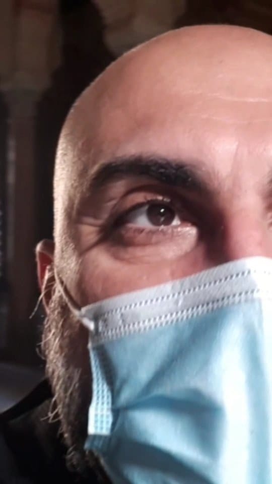 El clip alterna un plano oscuro de un pasillo o interior apenas iluminado por un haz de luz al fondo, con varios primeros planos selfie de un hombre calvo con barba y mascarilla quirúrgica…