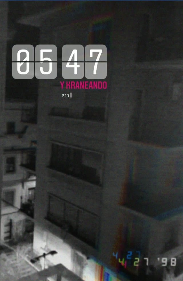 Toma nocturna fija de un edificio de apartamentos visto desde una ventana alta, con textura de video vigilancia (ruido, aberración cromática y una marca de fecha "4 27 98" en la esquina…